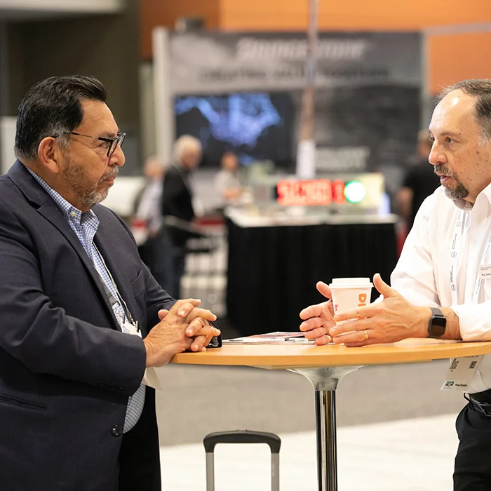 Two guys talking at a table with coffee