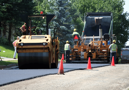 An asphalt spreader is used to place the first layer of asphalt on a city street renewal project.