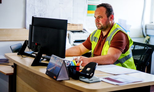 Construction Worker sitting on a computer at his desk